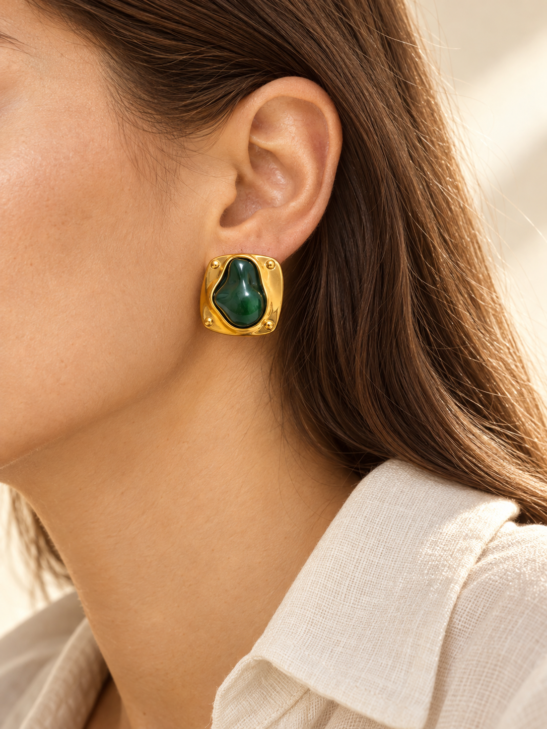 Detalle editorial de arete verde y dorado en modelo