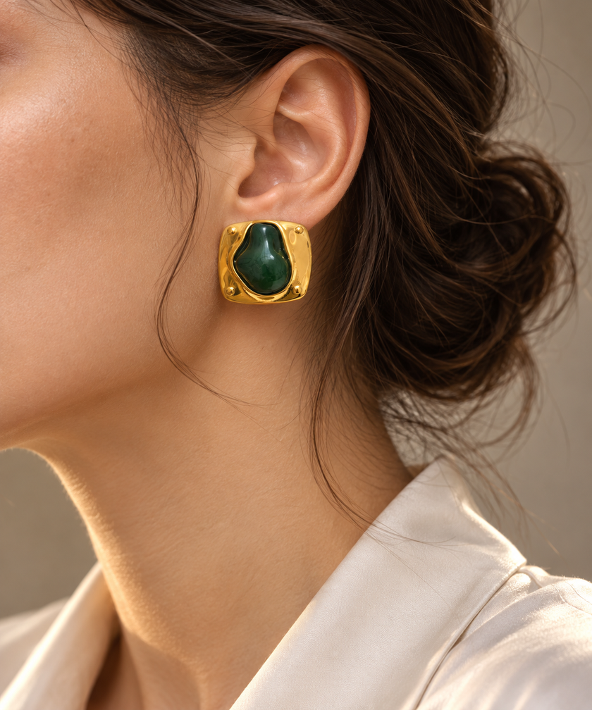 Detalle editorial de arete verde y dorado en modelo